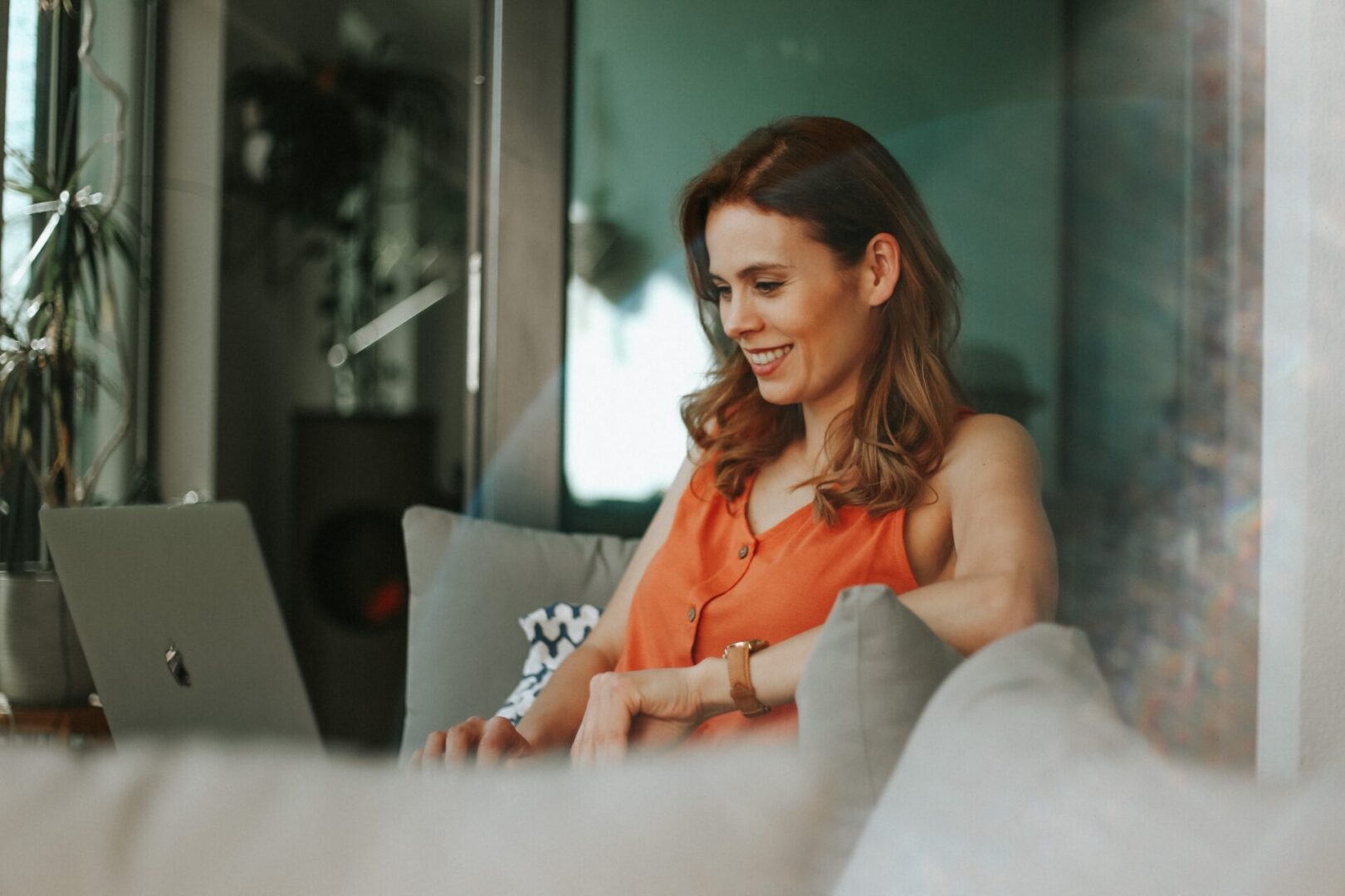 A woman sitting on top of a couch using her laptop.