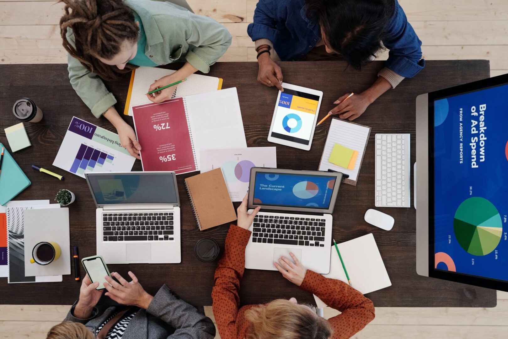 A group of people sitting around a table with laptops.