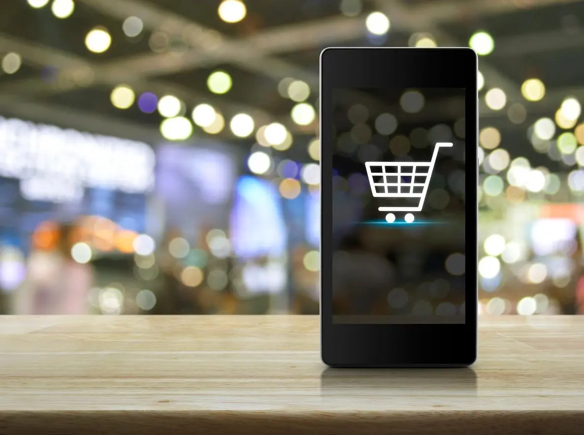 A smart phone with an image of a shopping cart on the screen.